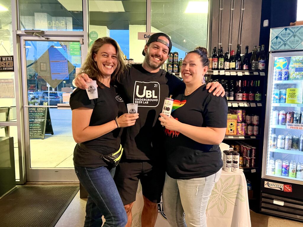 Three people smiling and holding Barfly THC drinks at a local popup event, celebrating new retail locations and showing where to buy Barfly.
